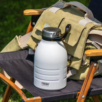 Gourde Isotherme 1,5L avec Paille Amovible, posés sur une siège de camping à côté d'un sac.