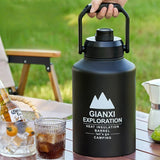 Gourde Isotherme 2L Noire avec Anse Robuste, posée sur une table de camping à côté d'un verre et d'une cafetière à l'italienne.