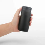 Mug Thermos Café Petit Format en Acier Inoxydable, de couleur noir, dans une main, sur un fond blanc.